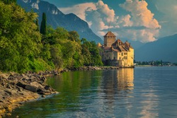 Popular Swiss touristic location with famous picturesque Chillon castle at Geneva lake and high mountains in background at sunset, Montreux, Switzerland, Europe