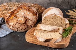 Fresh homemade leavened bread in the sun, partially sliced. Bread is located on a wooden surface. Hobbies, baking rye bread at sourdough at home. Healthy food concept, traditional craft bread. Closeup