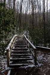 A long stairway made of wood rising to Mingo Falls in the Blue Ridge Mountains, North Carolina with a light dusting of snow