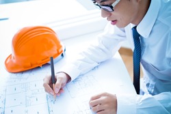 Closeup cropped image of a young male architect working on blueprints spread out on a table