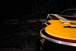 Black hard case with a wooden yellow acoustic guitar lying on a black velor fabric. Close up of an open wardrobe trunk with a stringed musical instrument. Black cover with acoustic guitar.