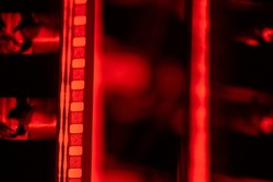 Vintage filmstrip in soft red light. Analog old strips of film for a photo or video camera close up. The concept of cinematography, photography, photographic memories.