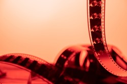 Vintage filmstrip in soft red light. Twisted analog old strips of film for a photo or video camera close up. The concept of cinematography, photography, photographic memories.