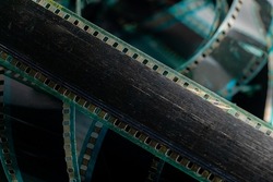 Black swirling strips of old analog film with scratches and scuffs. Photo or video film for films or pictures close up. The concept of retro cinematography, photography, photographic memories.