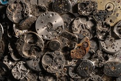 Top view of heap of metal internal parts of an old clock. Silver clockwork with gears and cogwheels. Rusty aged vintage watch parts. Disassembled clock mechanism of vintage clock. Close up.