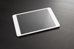White digital tablet on dark wooden table