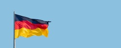 Banner with a national black red yellow flag of Germany and at blue sky background with copy space, details, closeup. Concept of nationality, citizenship and patriotism