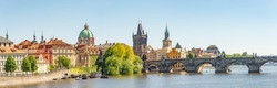 Panoramic view over magnificent Vltava river with tour boats, tourists and famous Charles Bridge and walking embarkment in historical downtown of Prague, Czech Republic at blue sunset summer sky