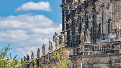 Old roof statutes of high ranked priests and saints lined up in Catholic Cathedral of Holy Trinity, Hofkirche in downtown of Dresden, Germany, details, at blue sky suny day