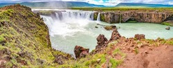 Scenic panoramic view of popular tourist attraction waterfall Godafoss in Iceland with tourists watching the sightseeing, summer, dramatic sky