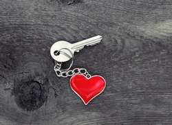 key with heart charm on old wooden table