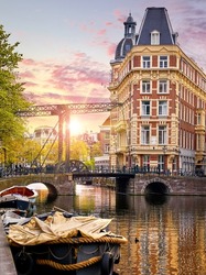 Amsterdam, Netherlands. Panoramic view of autumn Dutch city. Famous channel of Amstel river. Evening cityscape. Colorful sunset scene of famous travel destination in Europe. Romantic traveling place.