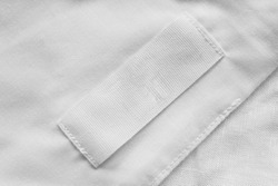White blank clothes label on white linen as a background