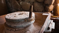 An ancient hand mill made of stones and wood. Flour grinding device. Authentic handicraft