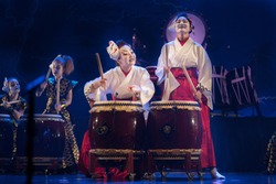 Traditional Japanese performance. Group of actresses in traditional kimono and fox masks drum taiko drums on the stage.