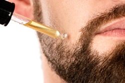 Closeup of male face and pipette with a oil for a beard growth