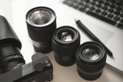 Photographer's workplace with a modern equipment. Mirrorless camera, laptop and prime lenses.
