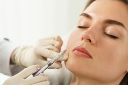 Female client during facial filler injections in aesthetic medical clinic