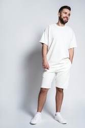 Handsome man wearing white sweatshirt and shorts against gray background