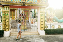 Young pretty female tourist is sightseeing an ancient buddhist temple in Thailand.