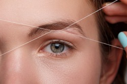 Close-up of female face during eyebrow correction procedure