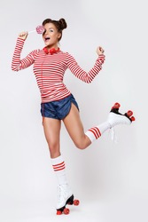 Beautiful woman in the roller-skates and with red headphones and lollipop in studio