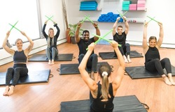 A Fitness Teachers with Green Drum Stick at the gym with a training group of peole
