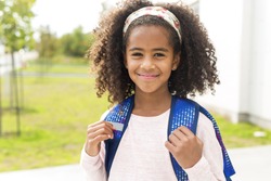 A cheerful african american primary school girl with backpack
