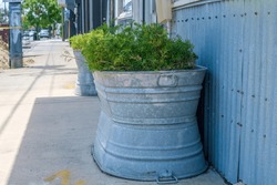 Selective focus of galvanized steel tubs being used as an outdoor planter on a city sidewalk