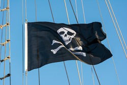Jolly Roger Black Pirate Flag With Human Skull On Blue Sky