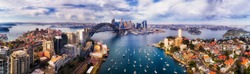 Wide aerial panorama of Sydney city CBD landmarks on shores of Sydney Harbour from Lower North Shore to distant Barangaroo.