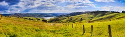 Green grazing farm land around Lake Lyell in Blue Mountains of Australia - life style agricultural cattle paddock fenced on hillsides in wide panoramic view.