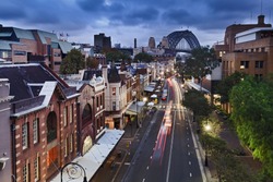 australia sydney the rocks historic district in the city view from top on george street illuminated houses and Sydney Bridge in the background at sunset
