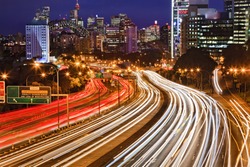 Australia NSW Sydney city Cahill expressway at sunset with long blurred traffic lights multi-lane motor road towards CBD, harbour bridge and illuminated landmarks