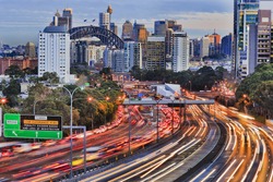 Long exposure blurred vehicle motion on multi-lane Warringah freeway going through North Sydney in Sydney, Australia. Headlights during rush hour commute towards Sydney harbour bridge and CBD towers.