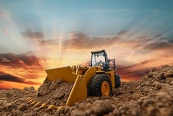 Selective focus with bucket,Wheel loader are digging the soil in the construction site on the sunset background .