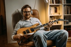 Caucasian artist is playing electric guitar at home.