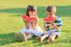 Little girl and a boy eating watermelon