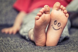 Concept of kids feet with smiley face drawing