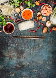 Various of asian cooking cooking ingredients and sauces with chopsticks  on rustic background , top view , place for text. Asian food concept: Chinese or Thai cuisine.