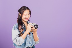 Portrait happy Asian beautiful young woman smiling excited wear denims holding vintage photo camera, teen female traveler female photographer, studio shot isolated on purple background