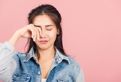 Asian portrait beautiful cute young woman wear denim bad mood her cry wipe tears with fingers, studio shot isolated on pink background, Thai female feeling sad unhappy crying with copy space