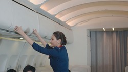 Flight attendant woman or Air hostess uniform service checking luggage cabin need to closed on the airplane