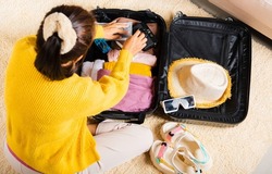 Preparing for travel in new normal. Woman packing clothes in luggage for new journey, Preparation travel suitcase at home, Travel vacation traveling after quarantine coronavirus pandemic concept