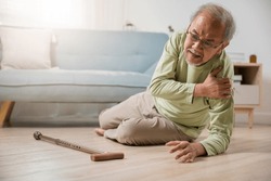 Sick senior old man falling down lying on the ground because stumbled at home alone with wooden walking stick in living room, elderly man grandfather having accident while walk with cane walker