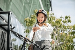Portrait smiling woman checking watch, Asian young businesswoman standing with bicycle check clock time on urban city street in morning time go to work at office, Business commuter transportation