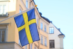 Swedish flag with colorful old town buildings on background