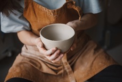 Pottery studio, artisan business, female potter hands holding ceramic bowl ready for firing in a kiln