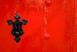 black keyhole on red wooden door