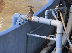 a photography of a blue boat with pipes and valves in the water, submarine style pipes and valves are connected to a blue boat.